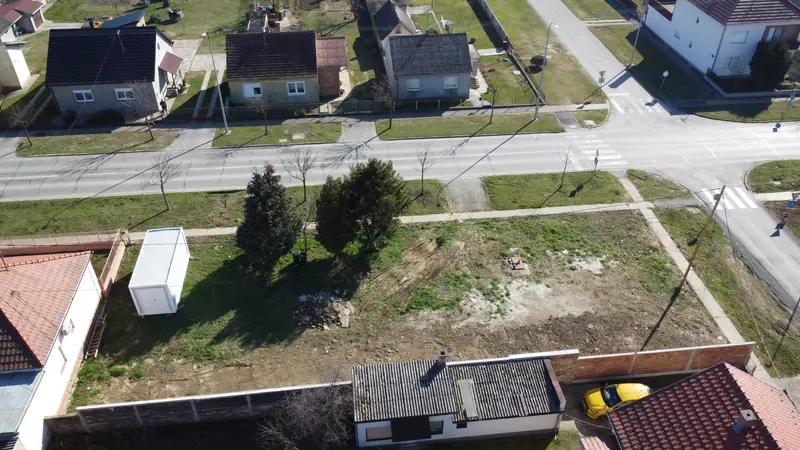 Snimka dronom: prazna ograđena kutna parcela s dva četinjača, prije početka radova.